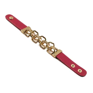 Dettaglio di bracciale in pelle rosa con catena in metallo dorato e bottoni a pressione