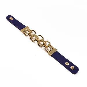 Dettaglio di un bracciale in pelle viola con grossa catena dorata e bottoni a pressione