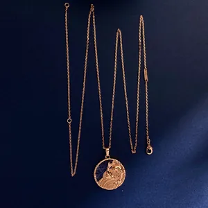Detail of rose gold zodiac coin pendant with blue semi-precious stone on silk background