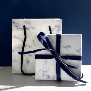 Elegante Marmor-Geschenkbox und passende Tragetasche mit blauer Seidenschleife im Detail