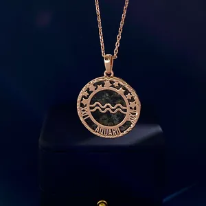 Macro shot of rose gold Aquarius zodiac coin necklace with green stone inlay and stars