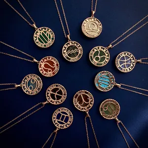 Macro view of rose gold zodiac coin pendants with semi-precious stones on blue fabric