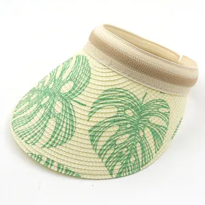 Detail of straw sun visor with monstera leaf print and striped elastic band strap