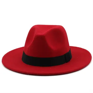 Detail view of a bright red wool felt fedora with a black ribbon band on a white background