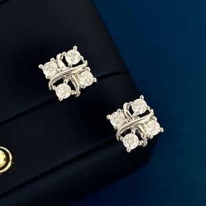 Κοντινό πλάνο από ασημένια σκουλαρίκια 18K με τέσσερα λαμπερά ζιργκόν σε σχέδιο χιαστί