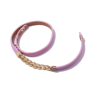 Macro detail of pink leather wrap bracelet with golden chain links and snap buttons