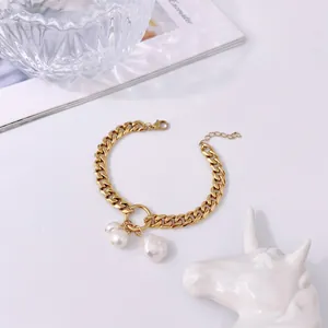 Dettaglio del bracciale a catena in oro 18K con perle barocche su sfondo minimale