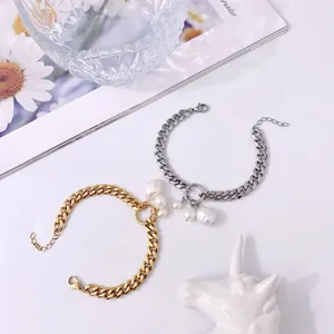 Dettaglio di bracciali a catena color oro e argento con ciondoli di perle barocche