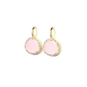 Détails macro de boucles d'oreilles dorées avec pierres roses facettées et bord en zircon