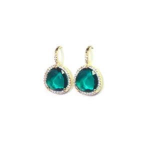 Détail de boucles d'oreilles poire en pierre verte avec halo de zircons étincelants