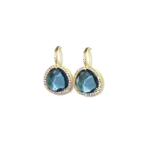 Détail de boucles d'oreilles goutte avec pierres facettées bleu foncé et accents dorés pavés