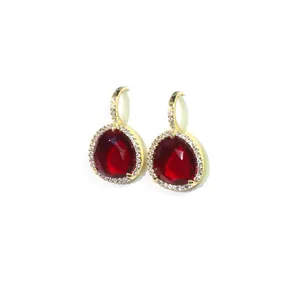 Boucles d'oreilles pendantes dorées avec cristal rouge et halo sur fond blanc épuré