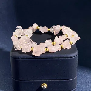 Detalle de cuentas de piedra natural de cristal rosa y cuentas doradas en la caja
