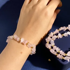 Detalle de pulsera de cuarzo rosa con cuentas doradas sobre fondo azul oscuro intenso