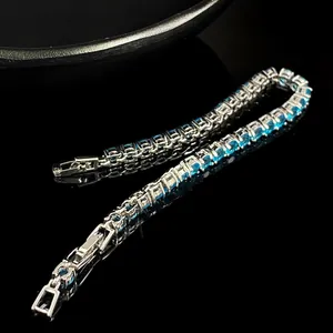 Macro view of emerald cut blue stones in a silver four-prong tennis bracelet setting