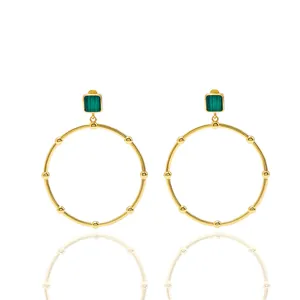 Detailed shot of gold hoop earrings with green malachite stone and polished beaded texture