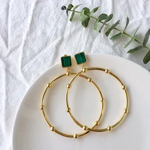 Detail of vintage gold hoops with green malachite inlay on a white decorative plate
