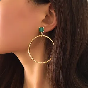 Detail of gold hoop earring featuring green malachite stone and textured metal beads