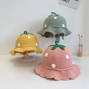 Detail of strawberry knitted baby bucket hats in yellow, green, and pink colors