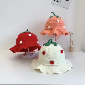Detail of hand-crocheted strawberry baby sun hats with green leaves and scalloped edge