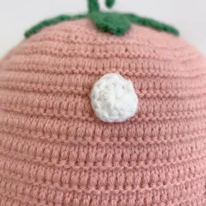 Macro detail of hand-knitted pink fruit-style baby hat showing tight crochet texture