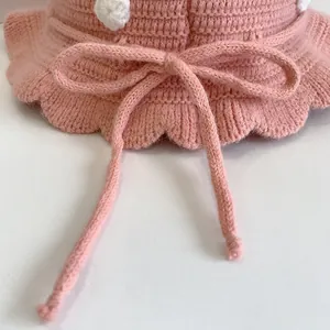 Detail of pink hand-crocheted baby sun hat with scalloped brim and knit bow decoration