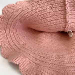 Detailed close-up of pink knit baby hat featuring wavy edges and soft wool texture