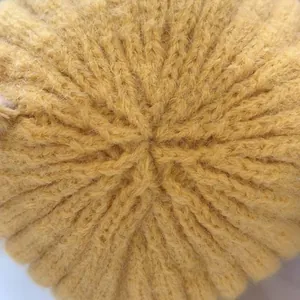 Makro-Detail der gelben Strickmütze mit Rippenmuster und radialer Naht an der Spitze