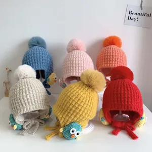 Dettaglio di cappelli colorati in maglia con paraorecchie, pompon e motivi a uccello