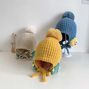Dettaglio di cappellini in maglia per neonati con pompon e fodera in pile beige e blu