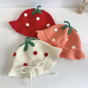 Detailed view of children's knit strawberry hat with leaf decor and wavy brim design