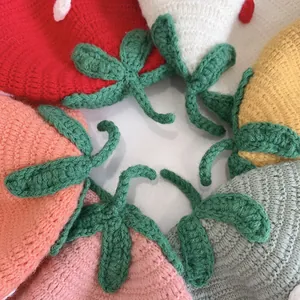 Top view of colorful knitted fruit-themed hats with green leaf accents for children