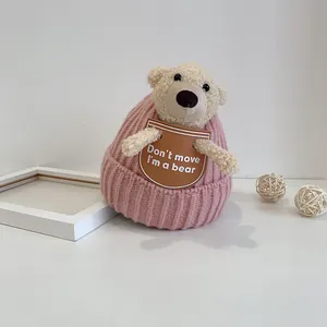 Pink infant winter knit hat featuring a cute 3D teddy bear decoration and warm textures