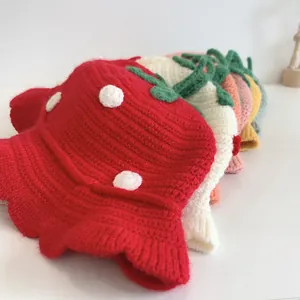 Detailed close-up of handmade strawberry-themed knitted baby hats in assorted colors