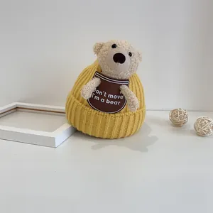 Warm yellow knit baby hat with a cute teddy bear doll and embroidered text design