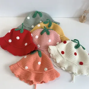 Detail view of colorful knitted strawberry hats for baby girls with wavy brims and ties