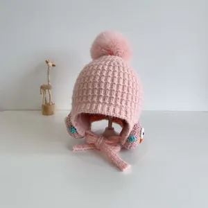 Dettaglio cappello in maglia rosa per neonati con pompon e ricamo a forma di uccello