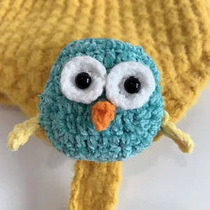 Dettaglio macro del cappello da neonato a gufo lavorato a mano con morbida texture ciniglia