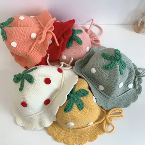 Colorful collection of children's knitted strawberry bucket hats on white background