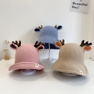 Detailed view of knitted baby bucket hats with cute antlers in pink, blue, and beige colors