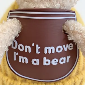 Macro detail of curly plush teddy bear wearing yellow knitwear with a silicone chest badge