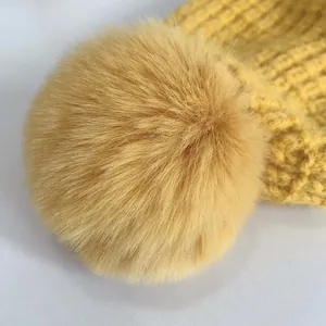 Dettaglio del cappello in maglia gialla per neonati con pompon e trama spessa
