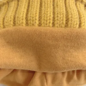 Macro detail of mustard yellow knit baby hat showing thick ribbed texture and soft lining