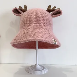 Pink knitted baby sun hat with cute deer antlers and ears on a white background