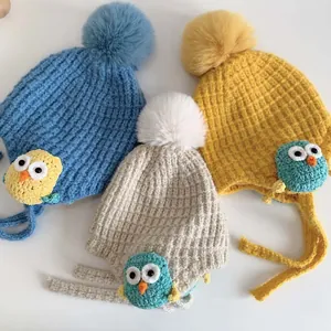 Dettaglio di berretti in maglia per neonati con pompon e toppe di gufi a fumetti