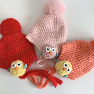Dettaglio di cappelli per neonati in maglia con paraorecchie, pompon e toppe gufo