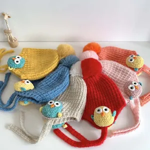Vista piatta di cappelli lavorati a maglia per neonati con pompon in vari colori