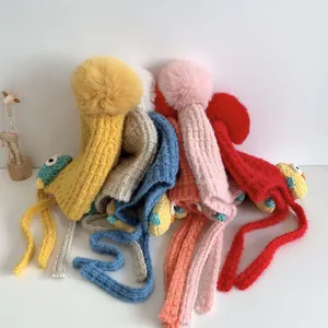 Dettaglio di cappelli invernali a maglia per bambini con paraorecchie e pompon