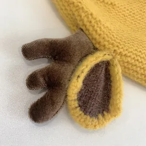 Close-up of yellow knit baby hat featuring plush deer antlers and soft woven texture