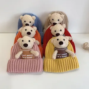 Close-up of six colorful ribbed knit baby hats with cute 3D plush bear decorations
